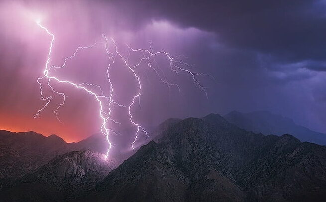 una imagen de un paisaje montanoso con nubes oscuras y relampagos